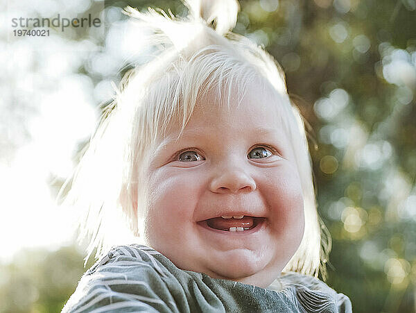 Smiling baby girl with blond hair in park