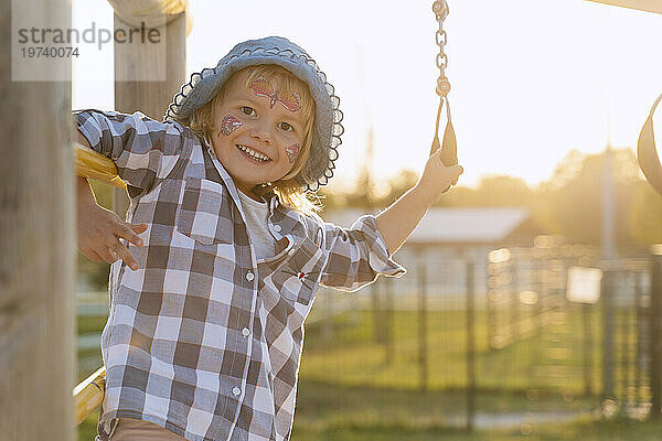 Smiling girl with face paint playing in playground at sunset