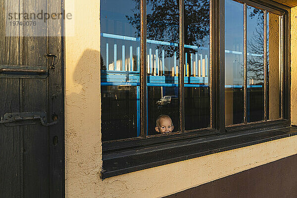 Lächelnder Junge  der durch ein stabiles Glasfenster schaut