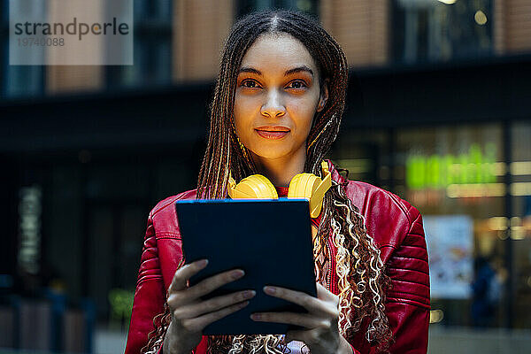 Selbstbewusste Frau mit geflochtenem Haar hält Tablet-PC