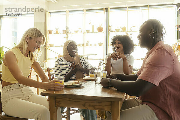 Fröhliche Freunde reden und essen im Café