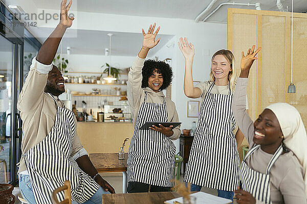 Glückliche Baristas mit erhobenen Händen feiern Erfolge im Café