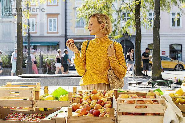 Lächelnde Frau kauft Äpfel auf dem Bauernmarkt