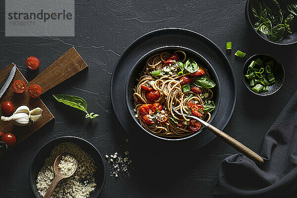 Schüssel mit veganen Vollkorn-Dinkelspaghetti mit Tomaten  Basilikum  Frühlingszwiebeln und Cashew-Parmesan