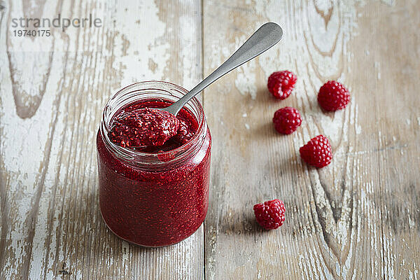 Jar of raspberry jam on wooden surface