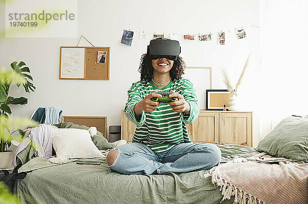 Happy girl wearing virtual reality simulators playing video game with controller at home