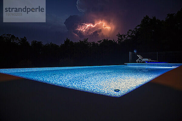 Beleuchtetes Schwimmbad mit Gewitter in der Nacht