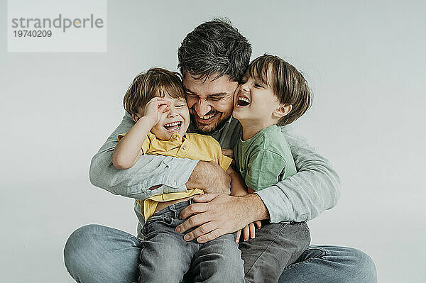 Happy father having fun and hugging children against white background