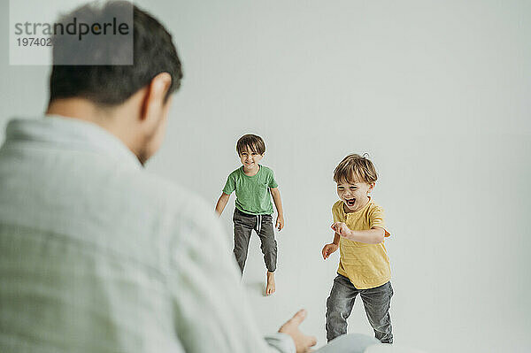Man playing with happy children against white background