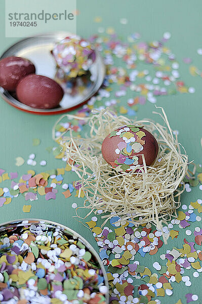 Easter egg in hay nest surrounded by confetti