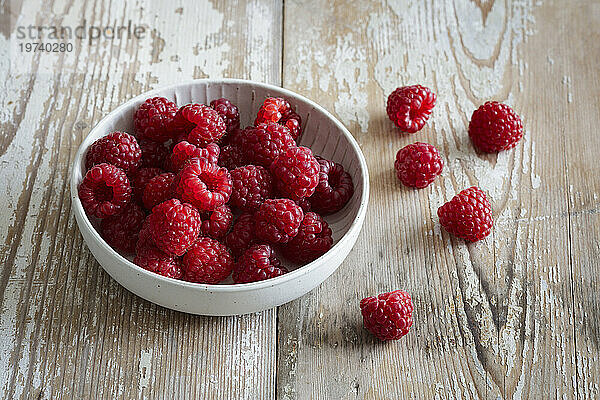 Bowl of fresh raspberries on wooden surface