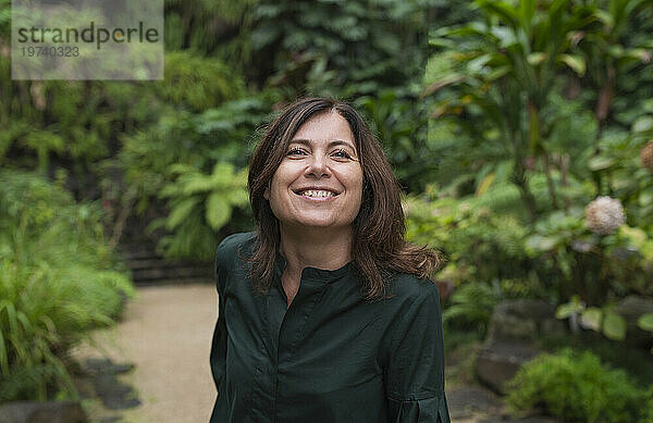 Lächelnde Frau im grünen Hemd im Botanischen Garten
