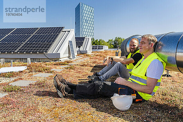 Zwei Solarpanel-Techniker machen eine wohlverdiente Pause auf dem Dach eines Firmengebäudes
