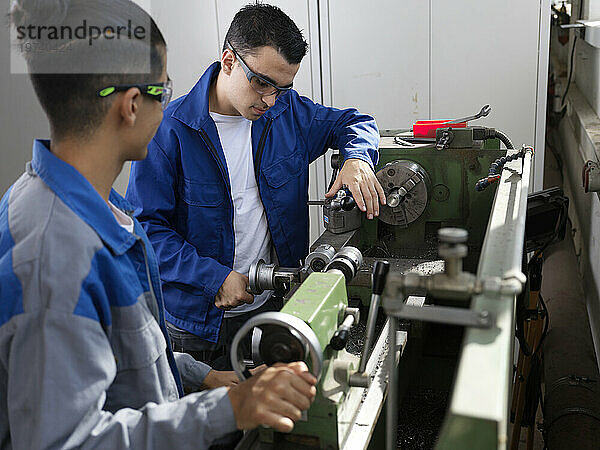Trainees operating lathe at workshop