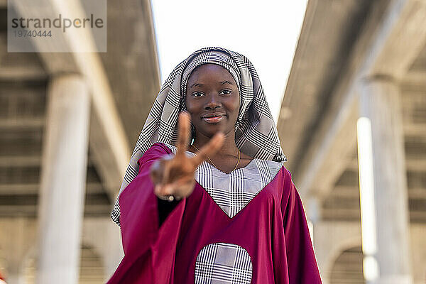 Young woman with hijab gesturing peace sign