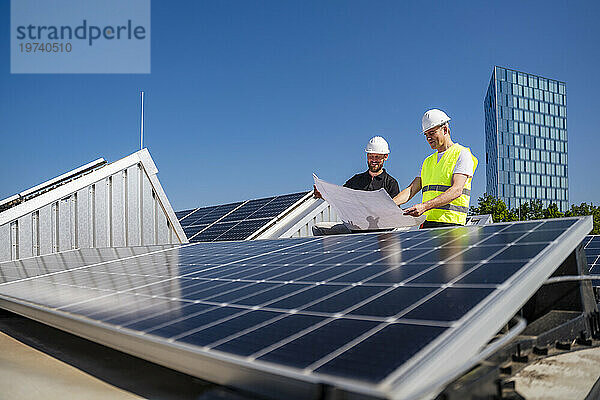 Zwei Techniker planen auf dem Dach eines solarbetriebenen Firmengebäudes