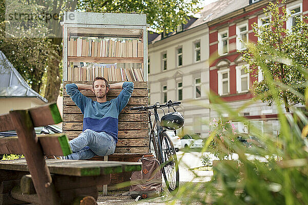 Reifer Mann entspannt sich und lehnt sich an den Bücherständer