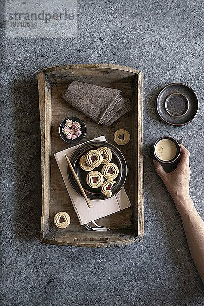 Tray with jam cookies  note pad  dish cloth  flower heads and cup of coffee