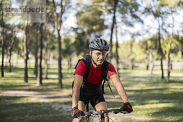 Reifer Mann mit Helm und Fahrrad im Wald