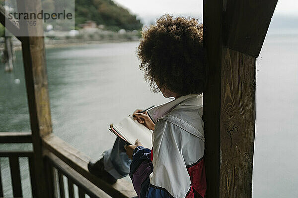 Frau schreibt Tagebuch in der Nähe eines Sees