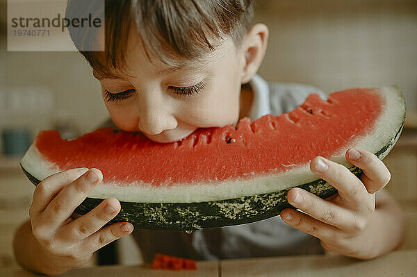 Junge isst zu Hause ein Stück Wassermelone