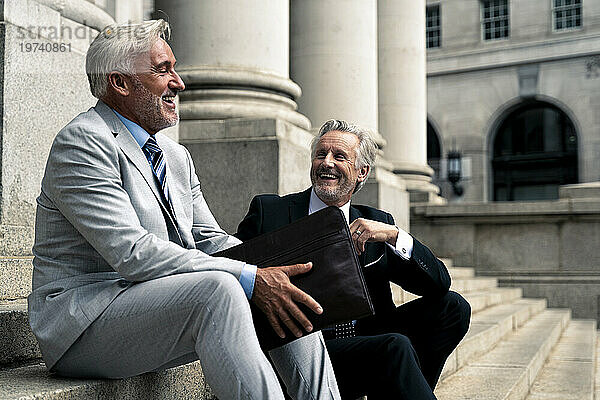 Glückliche ältere Geschäftsleute sitzen zusammen auf Stufen