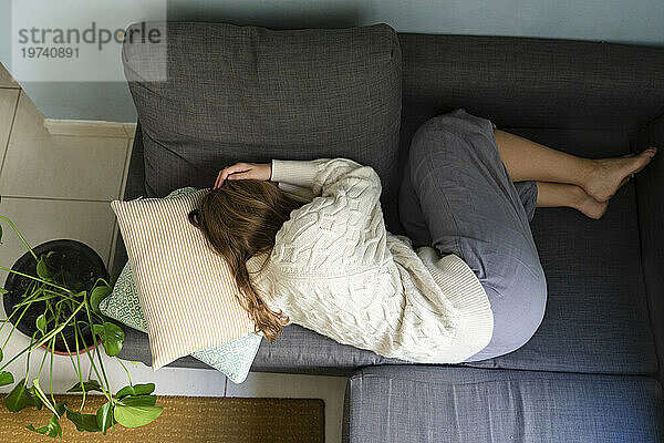 Frau mit Magenkrämpfen schläft zu Hause auf dem Sofa