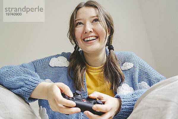 Glückliches Mädchen  das zu Hause Videospiel mit Controller spielt