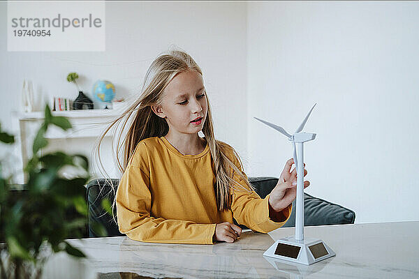 Mädchen berührt Windturbinenmodell auf Tisch zu Hause