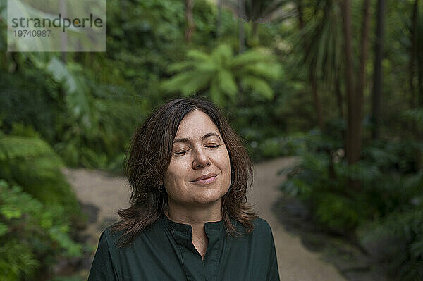 Lächelnde Frau mit geschlossenen Augen im Botanischen Garten