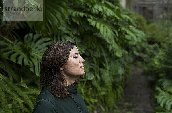 Frau mit geschlossenen Augen im Botanischen Garten