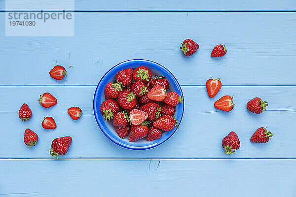 Bowl of ripe strawberries on blue wooden surface