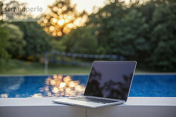 Bei Sonnenuntergang steht der Laptop am Pool