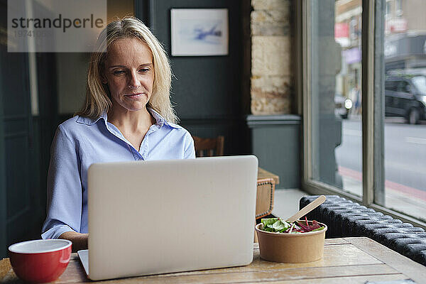 Lächelnder Freiberufler  der im Café am Laptop arbeitet