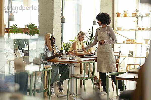 Lächelnde Kellnerin serviert Kunden im Café Essen