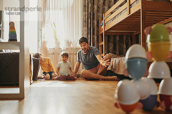 Fröhlicher Vater spielt mit seinen Söhnen zu Hause Bowling