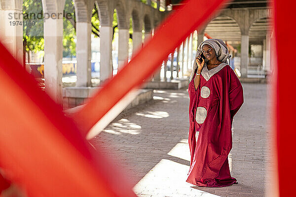 Junge Frau mit Hijab telefoniert unter der Brücke