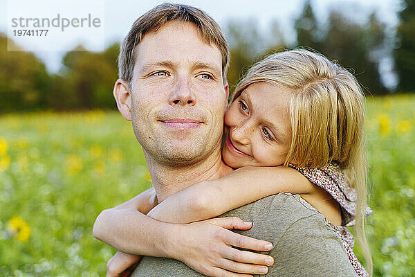 Smiling daughter embracing father in field