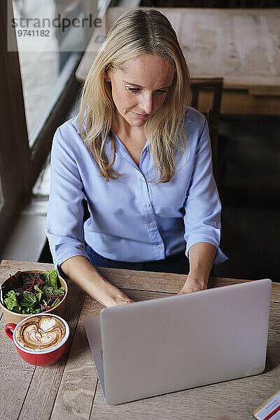 Blonder Freiberufler arbeitet am Laptop im Café