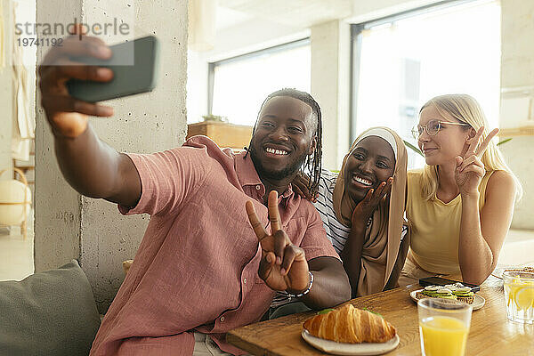 Lächelnder Mann macht Selfie mit Freunden im Café