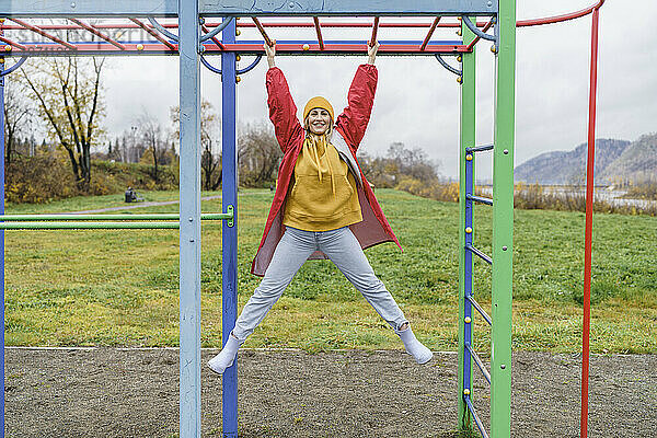 Lächelnde Frau hängt am Klettergerüst im Park