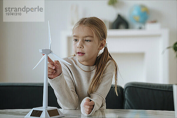 Blondes Mädchen berührt zu Hause Windturbinenmodell