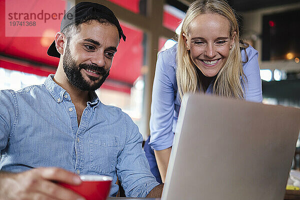 Lächelnde Freiberufler  die im Café am Laptop arbeiten