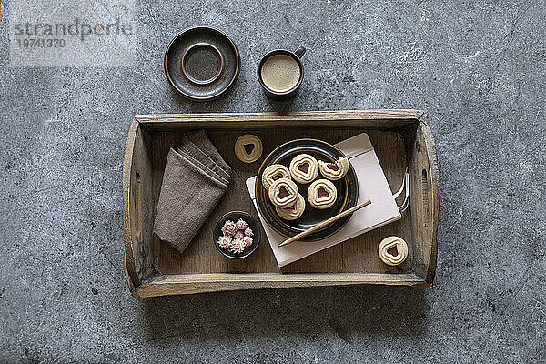 Tray with jam cookies  note pad  dish cloth  flower heads and cup of coffee
