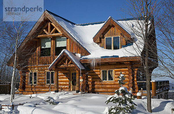 Schönes Blockhaus mit Schnee und Eiszapfen im Winter