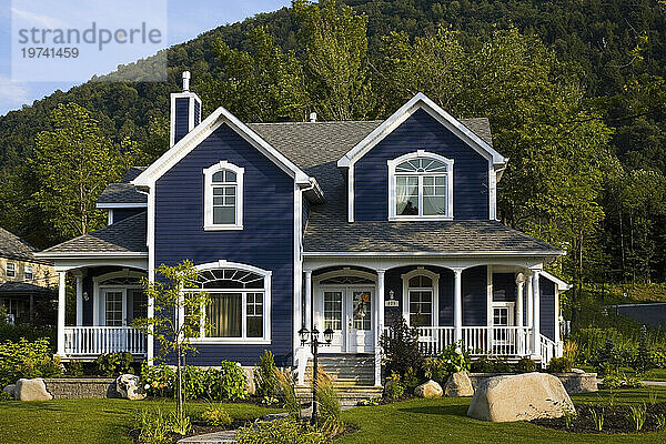 Großes Einfamilienhaus mit blauer Fassade  weiß getrimmten Fenstern und einem begrünten Vorgarten; Quebec  Kanada