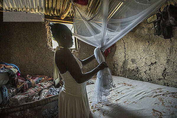 Frau richtet in Haiti Moskitonetze ein  um die Ausbreitung des Zika-Virus zu verhindern und die Gesundheit ihrer Kinder zu schützen; Marchand  Haiti