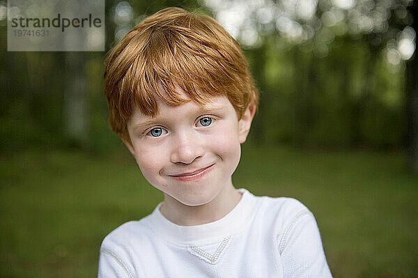 Nahaufnahme eines Außenporträts eines kleinen Jungen mit roten Haaren und blauen Augen; Crosslake  Minnesota  Vereinigte Staaten von Amerika