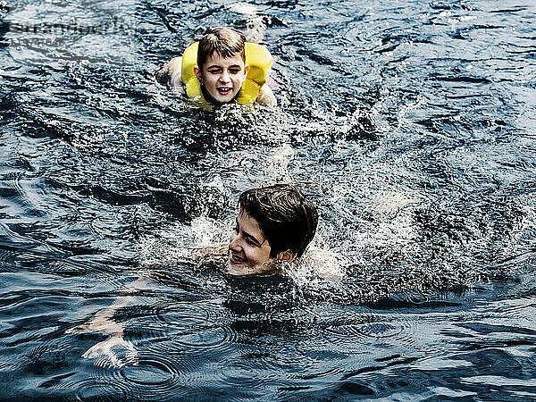 Zwei Brüder schwimmen im Urlaub in einem See und spielen im Wasser des Shuswap Lake; British Columbia  Kanada