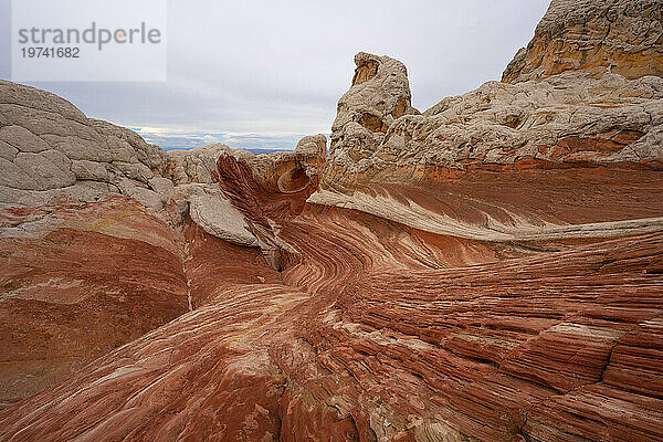 Malerische Aussicht auf wirbelnde Muster und hügelige Felsformationen unter einem wolkigen Himmel  die Teil der fremden Landschaft mit erstaunlichen Linien  Konturen und Formen in der wundersamen Gegend namens White Pocket in Arizona sind; Arizona  Vereinigte Staaten von Amerika